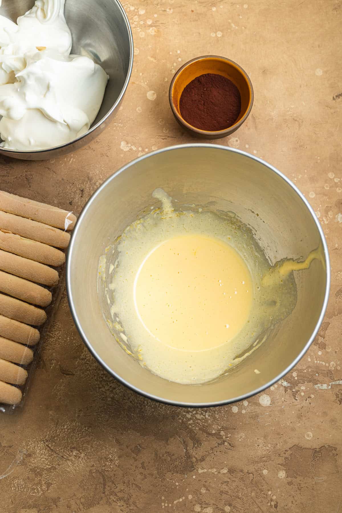 A bowl of whipped egg yolks with a bowl of whipped egg whites in the background.