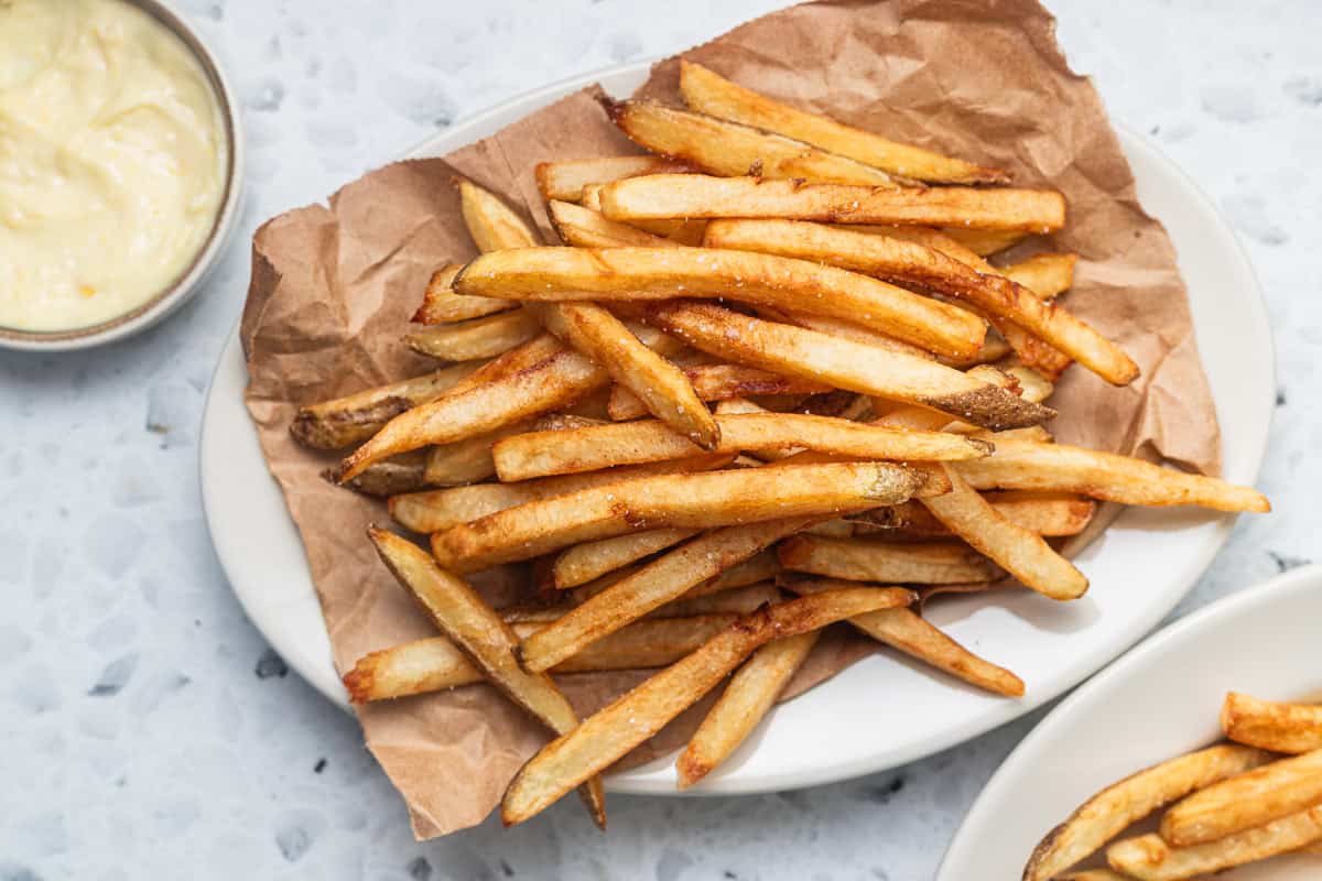 A platter of homemade fries with aioli in the background.