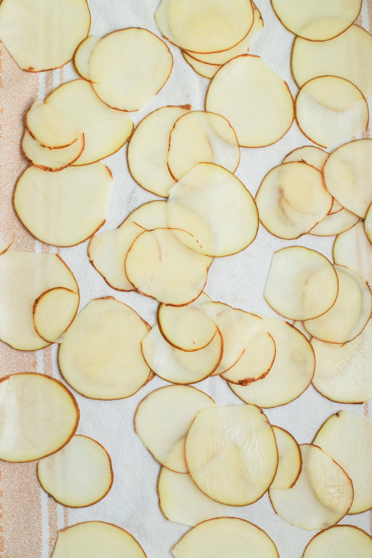 Slices of russet potatoes set over a kitchen towel.