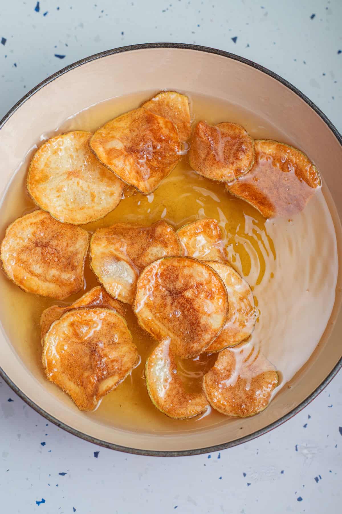 Potatoes being fried in a vat of oil.
