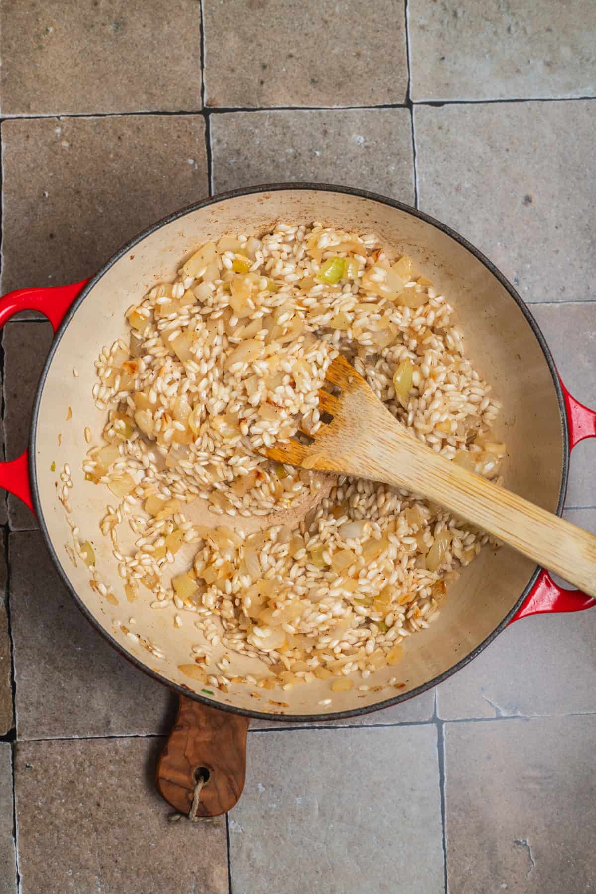A small Dutch oven with toasted rice and onions in it.