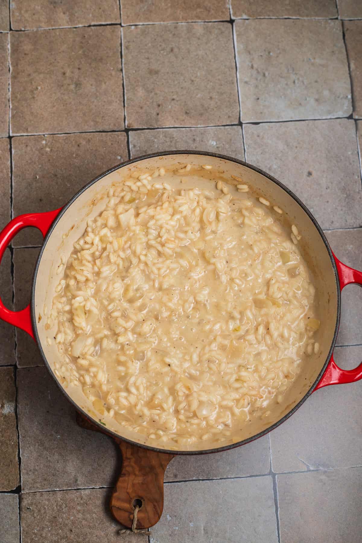 A small dutch oven with creamy risotto rice absorbing liquid.