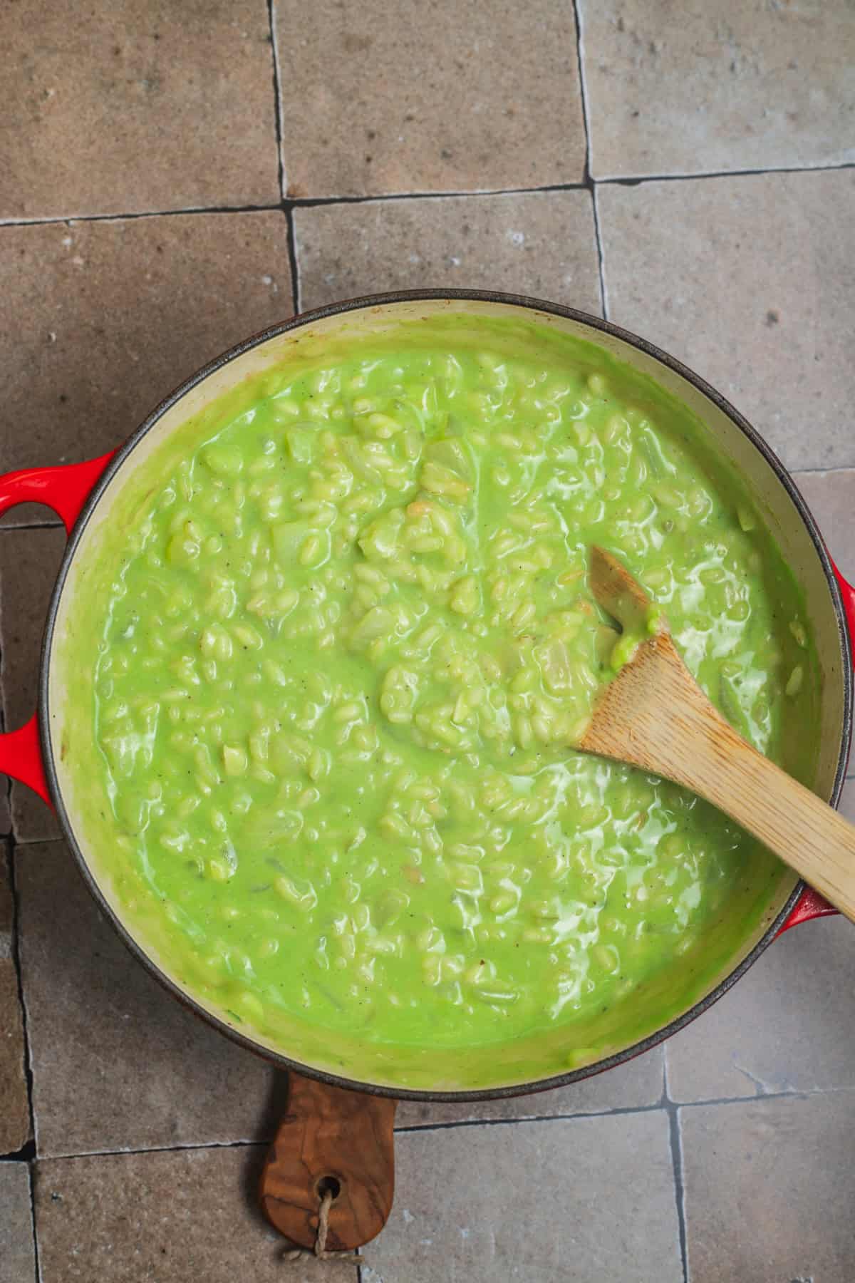 A small dutch oven with risotto suspended in a thick, vibrant green liquid.