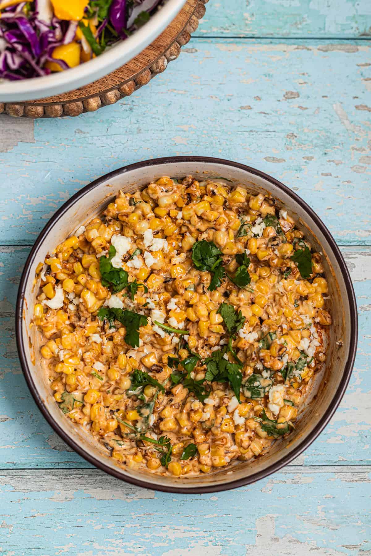 A bowl of creamy corn topped with cotija cheese and cilantro.