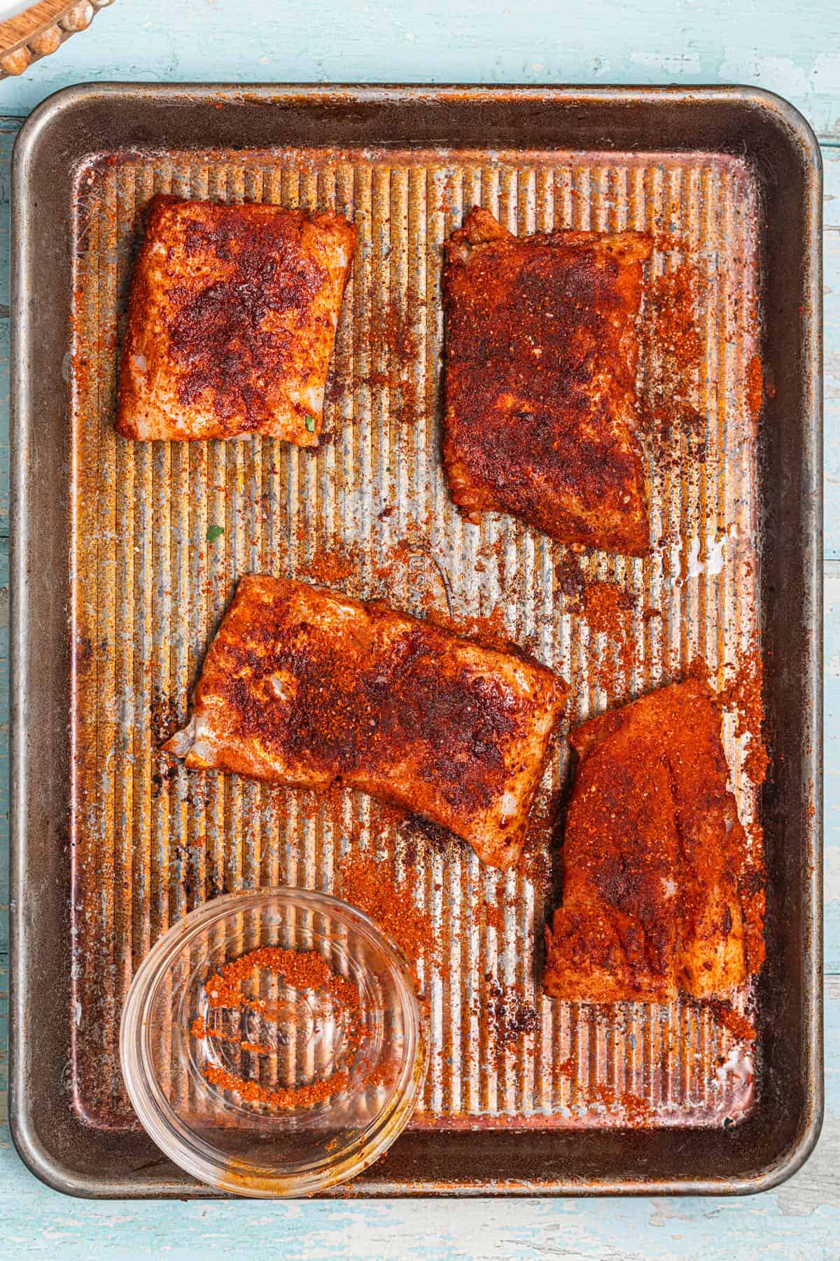 A baking sheet with fish coated in blackened spices.