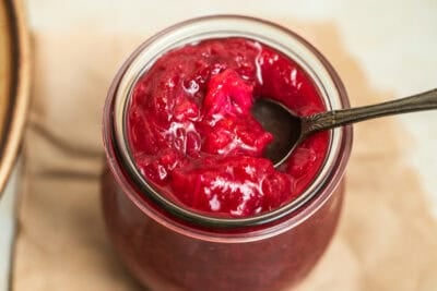 A jar of rhubarb jam with a spoon in it.
