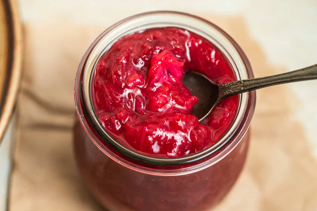A jar of rhubarb jam with a spoon in it.