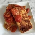 Two tofu cutlets topped with a cherry tomato sauce.