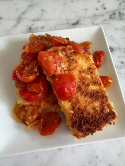Two tofu cutlets topped with a cherry tomato sauce.