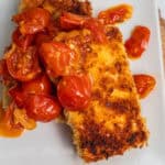 Two tofu cutlets topped with a cherry tomato sauce.