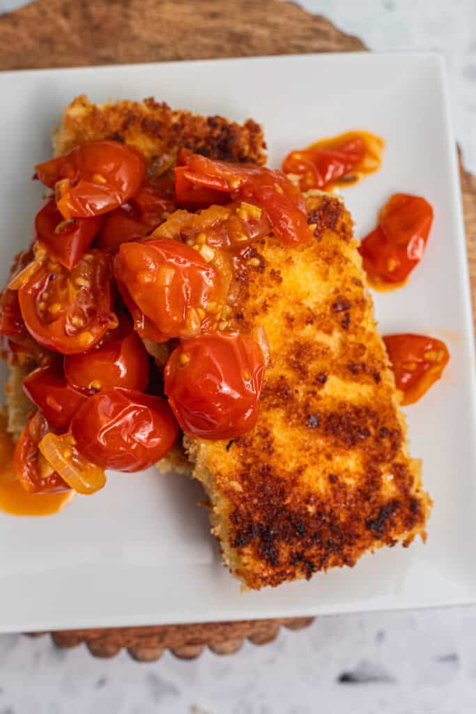 Two tofu cutlets topped with a cherry tomato sauce.