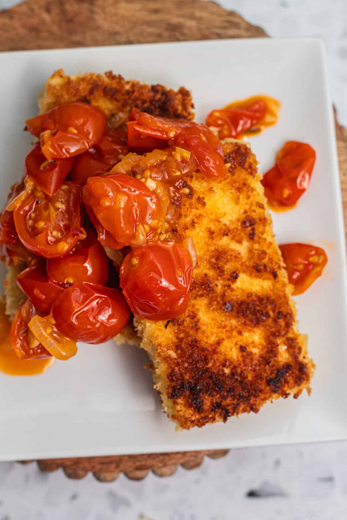 Two tofu cutlets topped with a cherry tomato sauce.