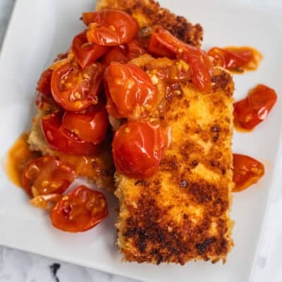 Two crispy tofu cutlets with cherry tomatoes on the top.