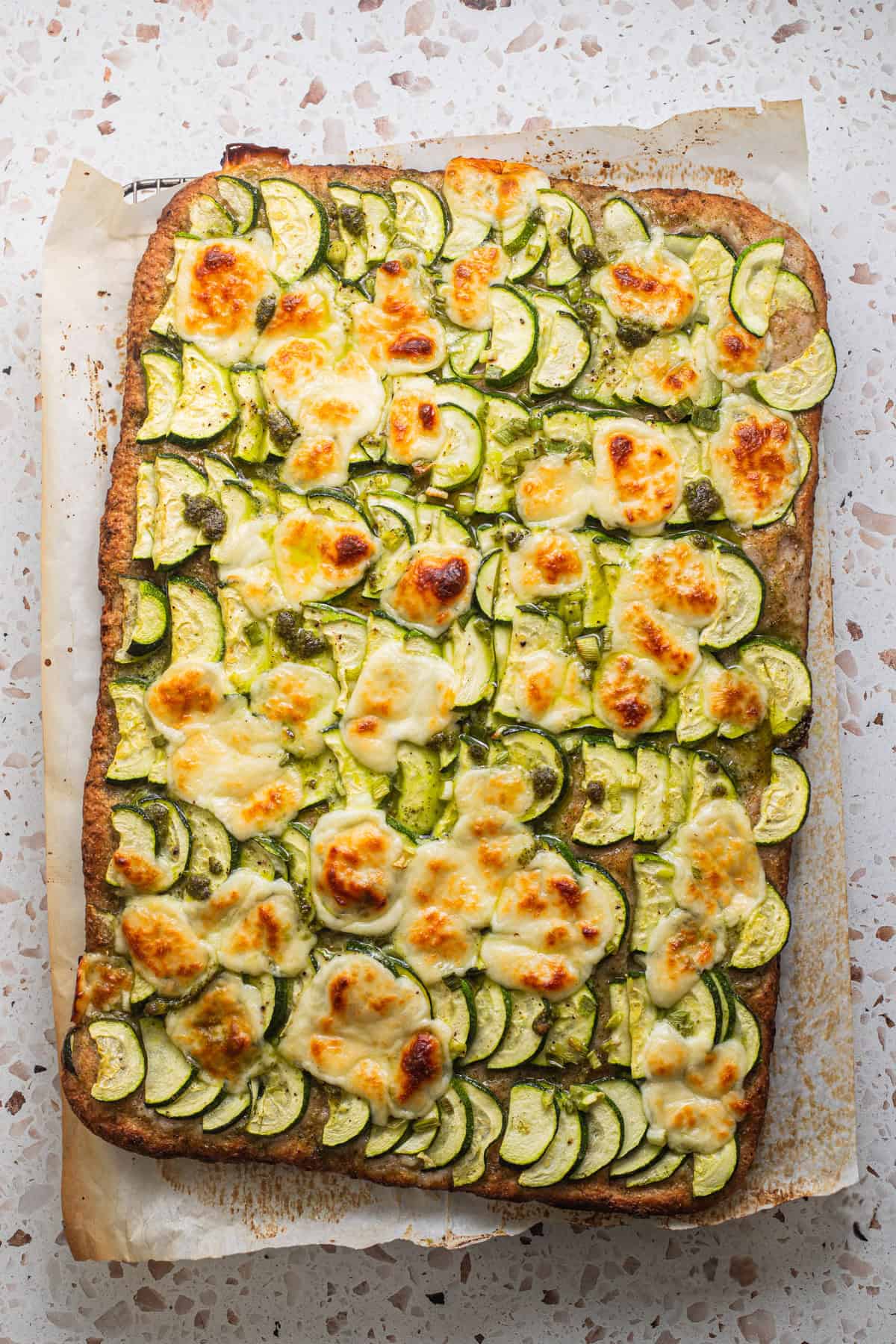 Zucchini slices on whole-wheat pizza dough baked with mozzarella.