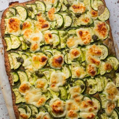 Layers of zucchini slices on pizza topped with golden mozzarella.