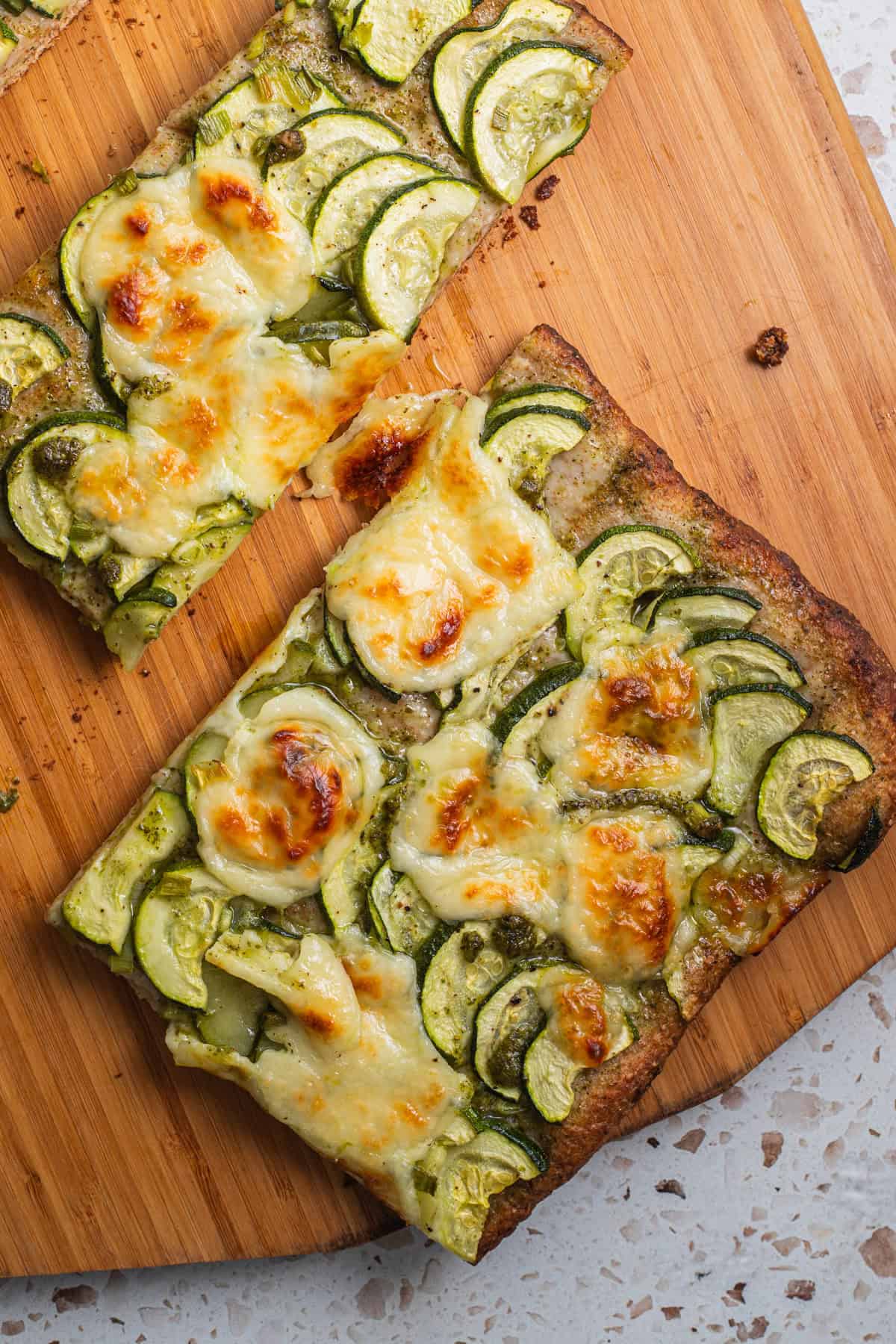 Slices of zucchini pizza topped with browned mozzarella.